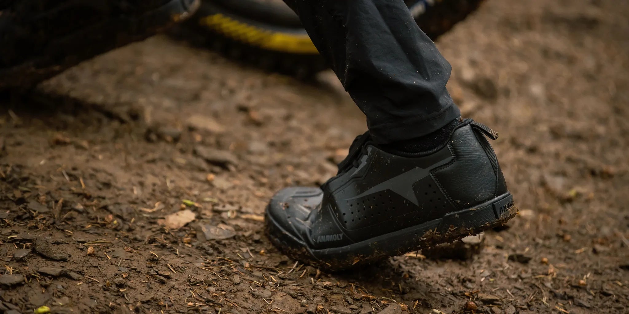 Mountain biker walking bike up rocky trail wearing flat pedal mountain bike shoes